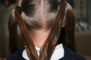 Back view of young girl's hair being styled into "Y" braid hairstyle