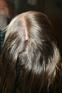 Back view of young girl's hair being styled into "Flip Braided Heart" hairstyle