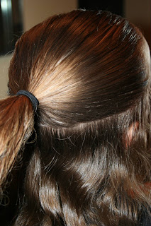 Side view of young girl's hair being styled into "Flip Braided Heart" hairstyle