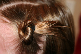 Side view of young girl's hair being styled into "Two Messy Twists on Top" Hairstyle