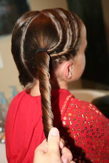 Side view of Young girl's hair being styled into "Triple Twists and Messy Buns"