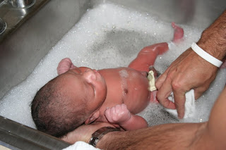 Giving our adopted infant baby boy his first bath in the hospital