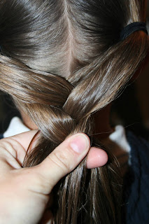 Close up view of young girl's hair being styled into "Y" braid hairstyle