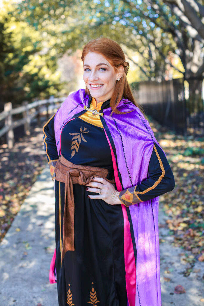 Women with red hair stand with her arms on her hips wearing costume.