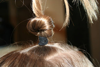 Close up view of young girl's hair being styled into "Top-Knot with Banded" Ponytail