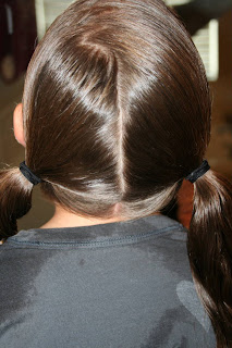 Back view of young girl's hair being styled into "Basic Twisty Buns" hairstyle