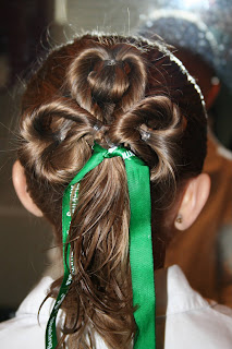 Back view of young girl modeling "Three-Leaf Clover Twists" hairstyle with green ribbon accessory