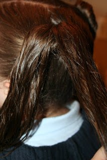 Side view of a young girl's hair being styled into “Two Hearts Twist” hairstyle