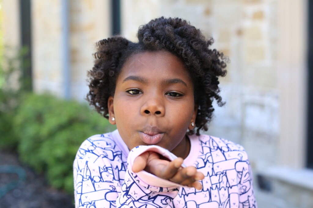 Young girl with Bantu Knots blows a kiss to the camera