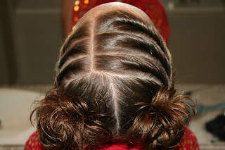 Top view of young girl's hair being styled into "Curls After Triple Twists w/ Messy Buns" hairstyle