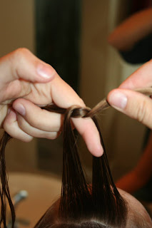 Close up view of young girl's hair being styled into "Knots into Side Ponytail" hairstyle