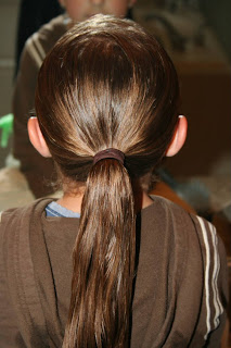 Young girl's hair being styled into "Pretzel-Twist Messy Bun"