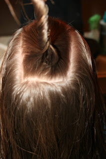 Close up view of young girl's hair being styled into "Holiday Twisty Buns" hairstyle