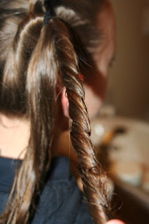 Side view of young girl's hair being styled into "Two-Leaf Clover" hairstyle