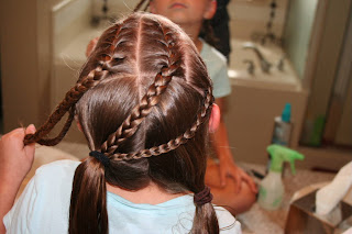 Back view of girl's hair being styled in "Criss-Cross French Braids"