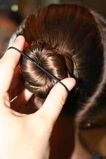 Side view of young girl's hair being styled into "Basic Twisty Buns" hairstyle