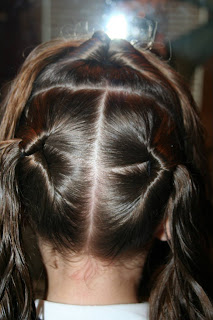 Back view of young girl's hair being styled into "Best Three-Leaf Clover" hairstyle