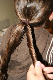 Young girl's hair being styled into "Pretzel-Twist Messy Bun"