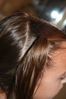 Side view of young girl's hair being styled into "4 Messy-Pigtail Twists" hairstyle