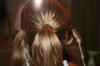 Back view of young girl's hair being styled into "Hair Headband" hairstyle