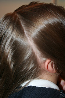 Side view of a young girl's hair being styled into “French Designer Heart” hairstyle