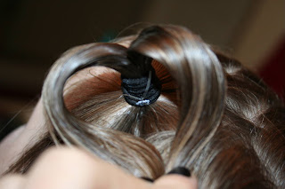 Close up view of a young girl's hair being styled into “Heart Pigtail” hairstyle