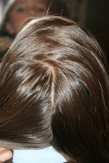 Back view of young girl's hair being styled into "Double-French Braids w/Messy Flips"