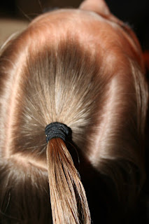 Close up view of young girl's hair being styled into "Holiday Twisty Buns" hairstyle