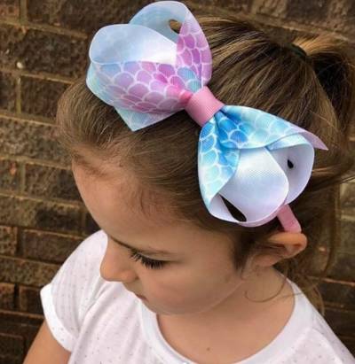 Combed Back Hairstyle With Ponytail And Statement Bow Hair Band On Top